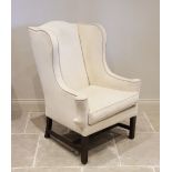 A George III style wing back fireside armchair, early 20th century, in cream fabric applied with