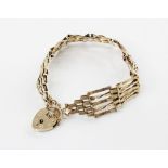 A 9ct gold gate-link bracelet, 17cm long, suspending a heart-shaped padlock fastener, 14mm x 19mm,