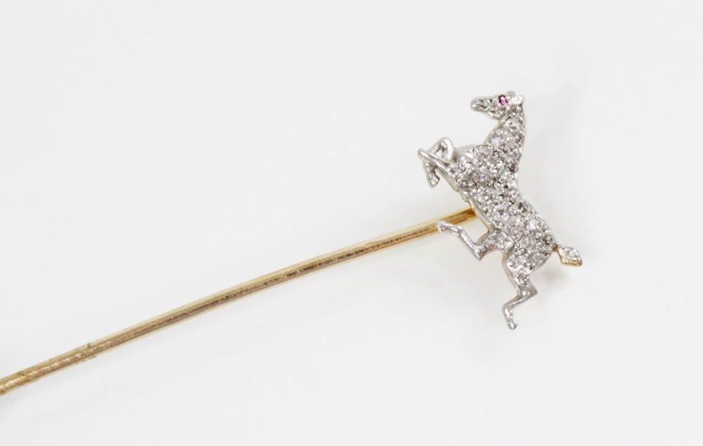 An early 20th century diamond and ruby horse stick pin, the horse modelled in gallop and set with