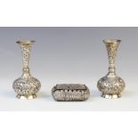 A pair of Burmese white metal posy vases, each with compressed circular bodies with tapering necks