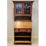 An early 20th century oak Arts and Crafts bureau bookcase, the pair of leaded glass doors opening to