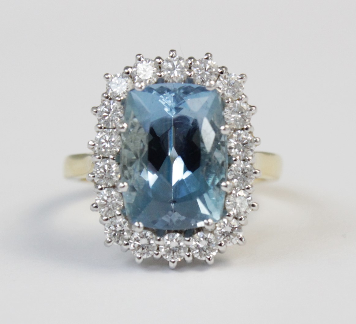 An aquamarine and diamond 18ct gold cluster ring, the central rectangular mixed cut aquamarine (