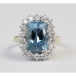 An aquamarine and diamond 18ct gold cluster ring, the central rectangular mixed cut aquamarine (