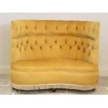 An early 20th century button back love seat, upholstered in yellow velour, the wrap around high back