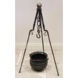 A 19th century iron cauldron and tripod stand, the tripod with a brass spherical finial above