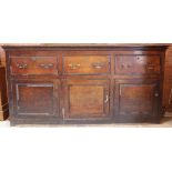 A George III oak dresser base, with three drawers above three cupboard doors,
