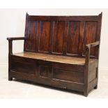 A 17th century oak box settle of cottage proportions, the five panel back above a twin box