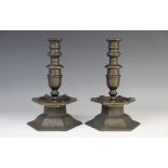 A pair of Arts and Crafts style bronze candlesticks, the hexagonal leaf cast plinth base below a