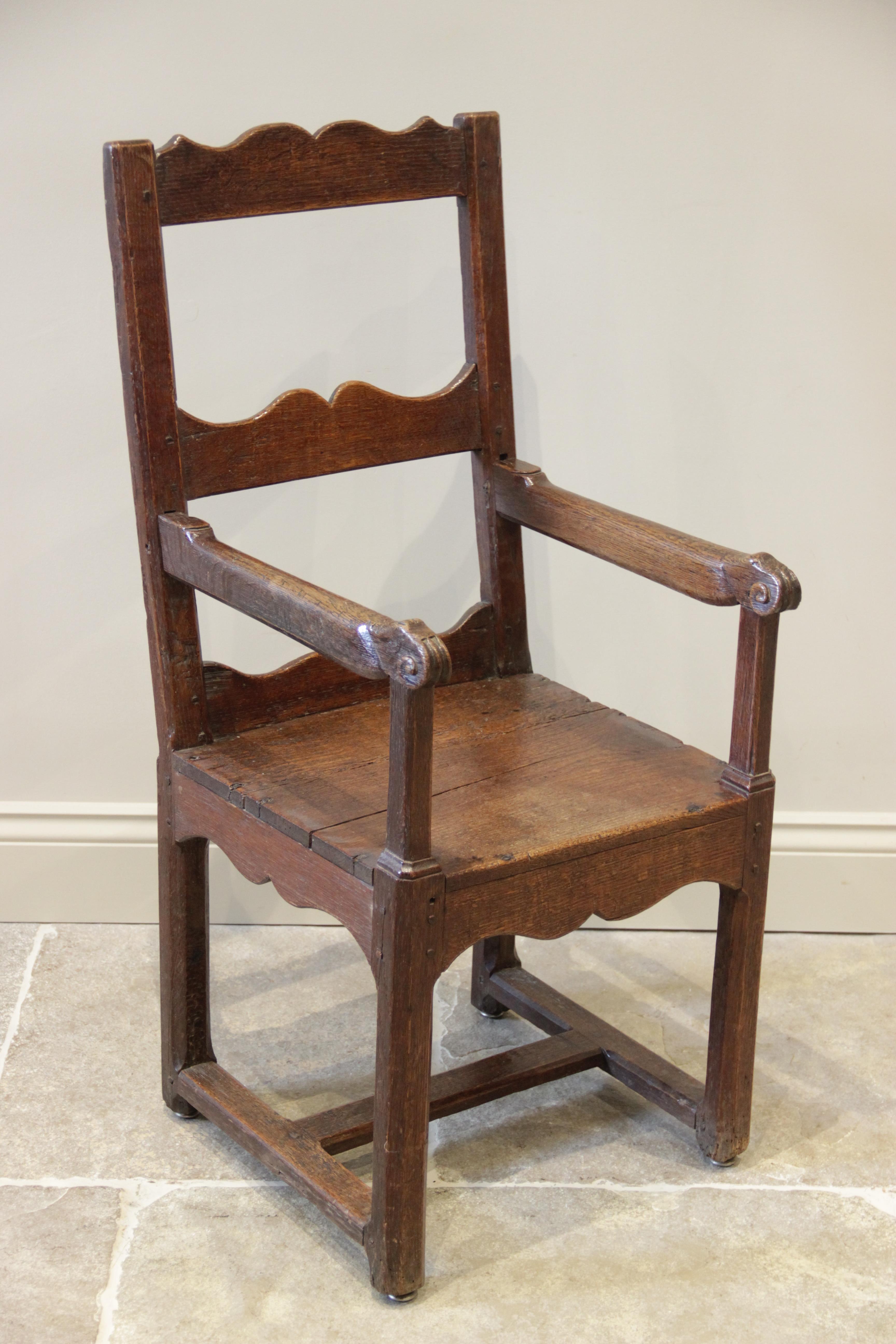 A 16th century jointed oak armchair, the two wavy back rails supported on chamfered supports