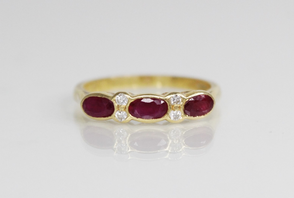 A ruby and diamond 18ct gold ring, comprising three (untested) oval mixed cut rubies, each