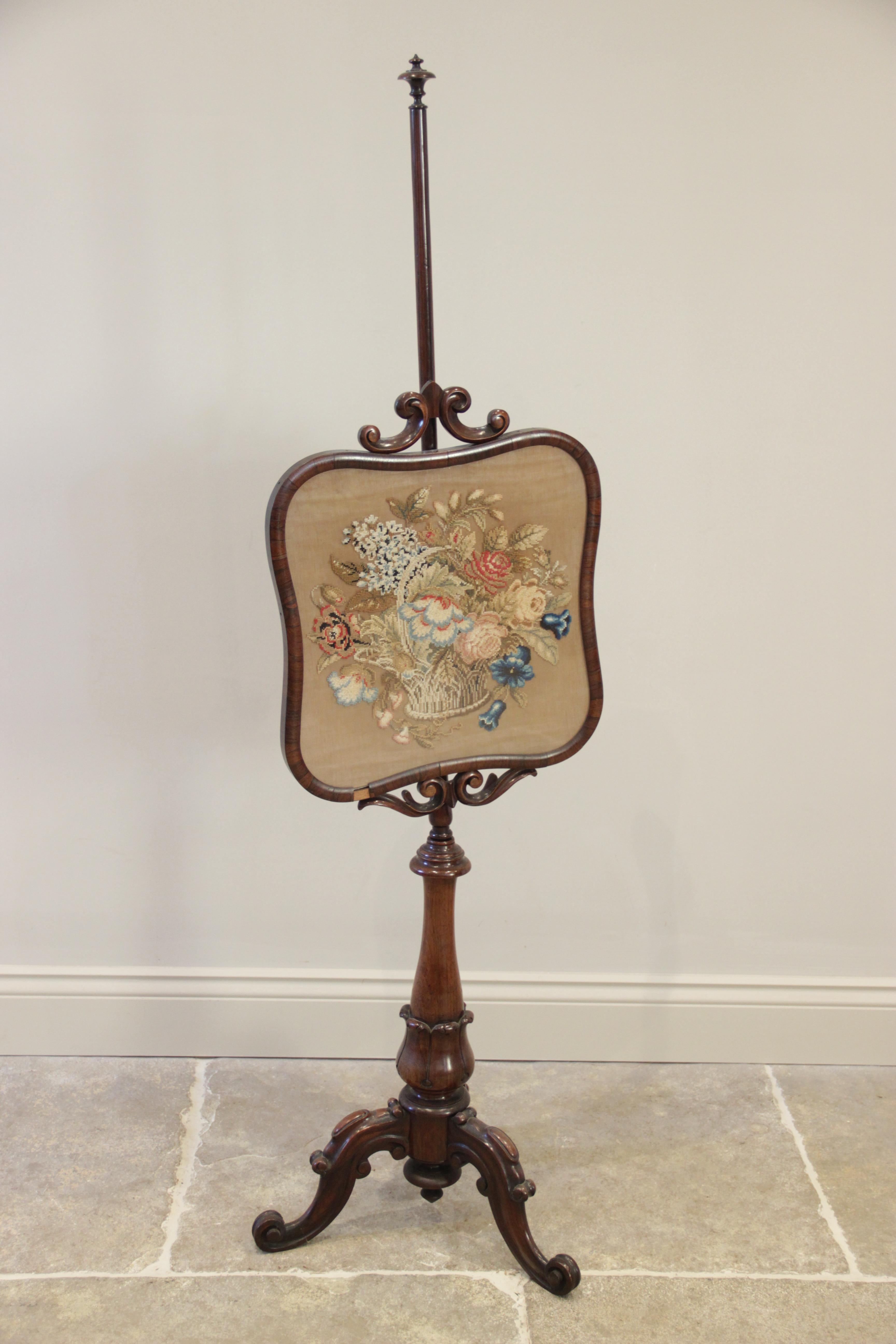 An early Victorian rosewood pole screen, the quatre-form glazed foliate Berlin work panel, applied