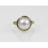 A 14ct gold mabe pearl dress ring, the central pearl (measuring 12mm diameter), collet set to the