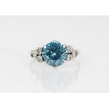 A zircon and diamond ring, the central round mixed cut blue zircon (measuring 8.65mm diameter),