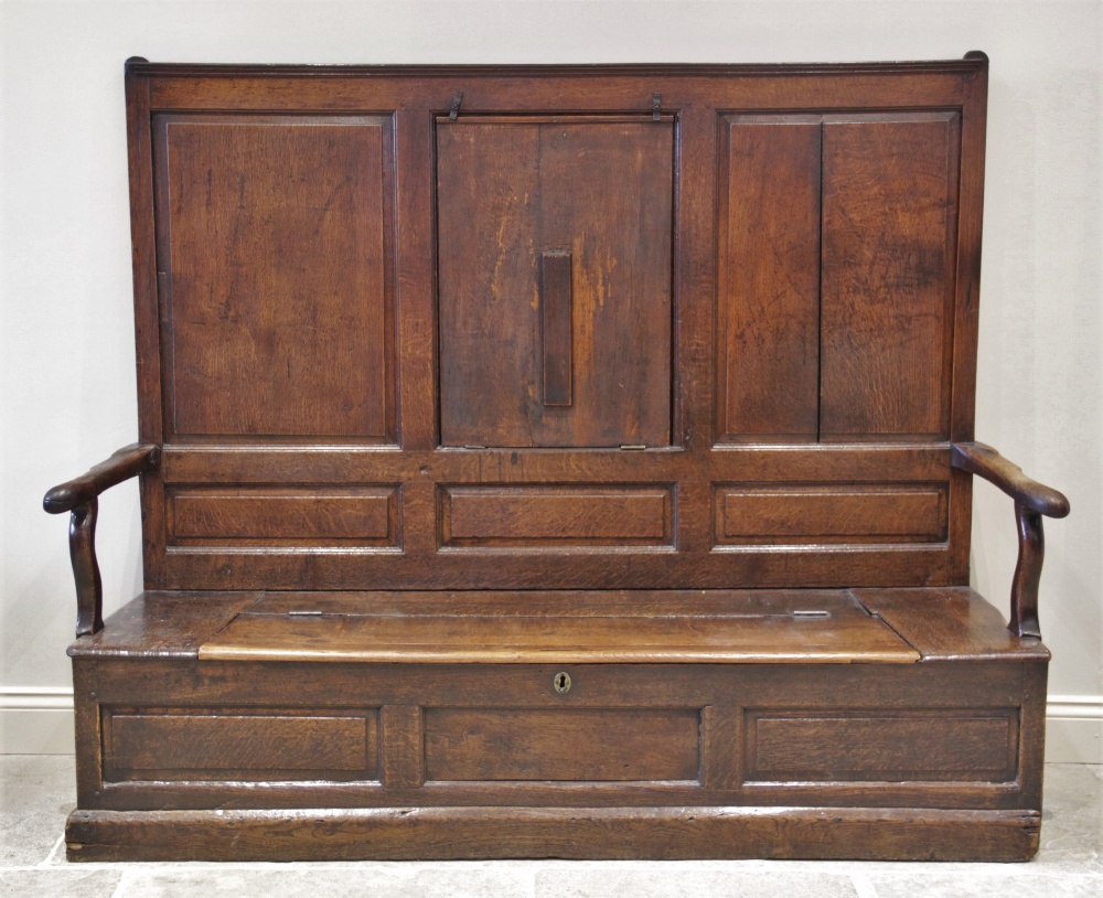 A late 17th century oak box settle, the high back with a central hinged table top flanked by fielded