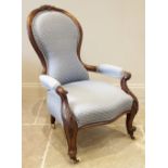 A Victorian walnut spoon back open armchair, in blue fabric, with a leaf carved crest above the
