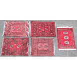 Four small Persian pattern wool rugs, each with a burgundy ground centred with twin octagonal