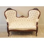 A Victorian mahogany framed double spoon back sofa, the shaped button back applied with carved leafy