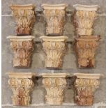 A collection of nine carved pine architectural capitals, each carved with leaf and scroll detail,