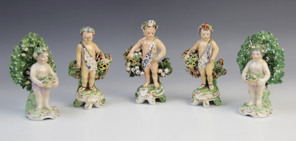 Three Derby bocage figures, late 18th century, each modelled as a putti holding a flower basket on a