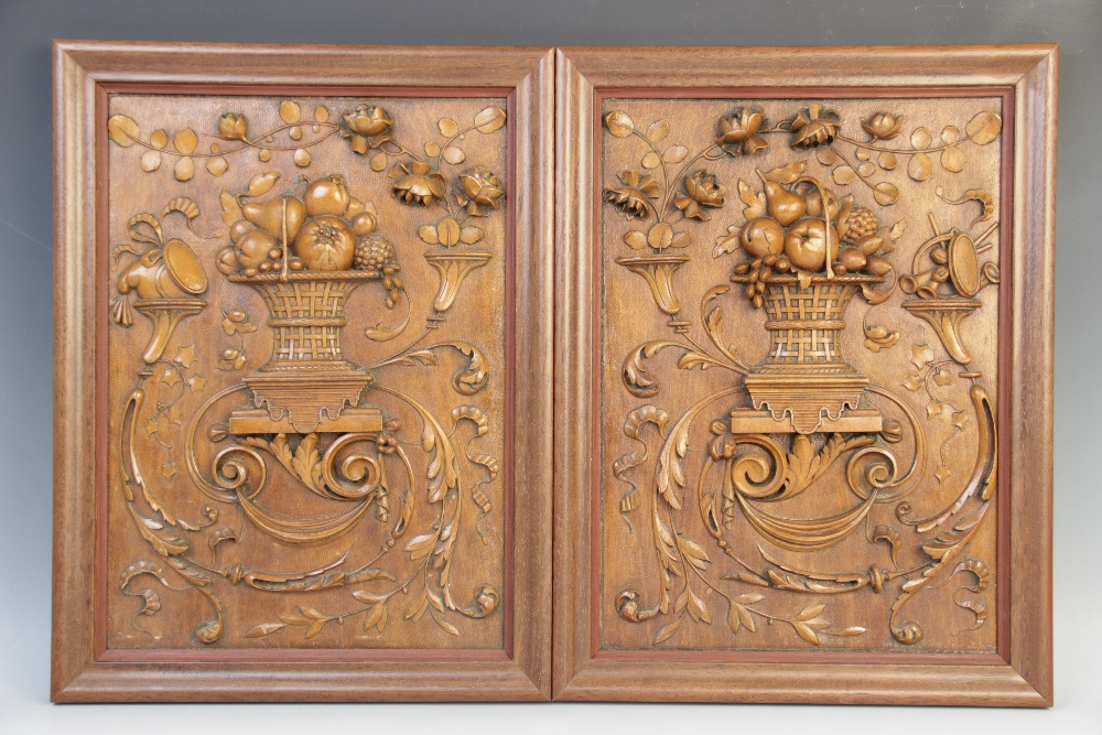 A pair of stained hardwood carved panels, each carved in relief with a basket of fruit within
