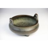 A Chinese bronze censer, of squat bulbous form with loop handles raised on three tapered feet,