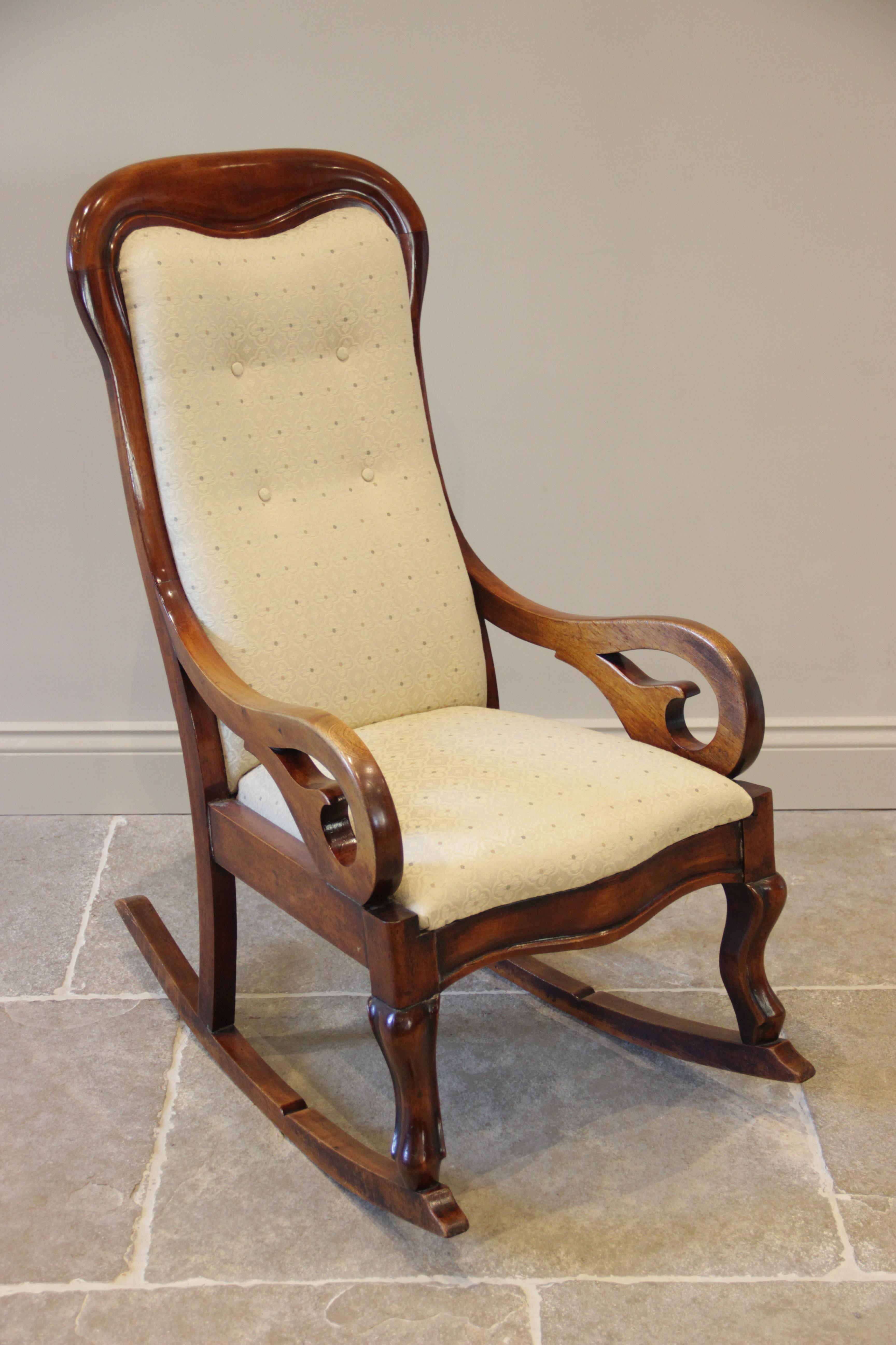 A Victorian mahogany framed rocking chair, the shaped button back within a mahogany frame