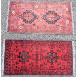 Two small Persian pattern wool rugs, each centred with a pair of floral medallions upon a red
