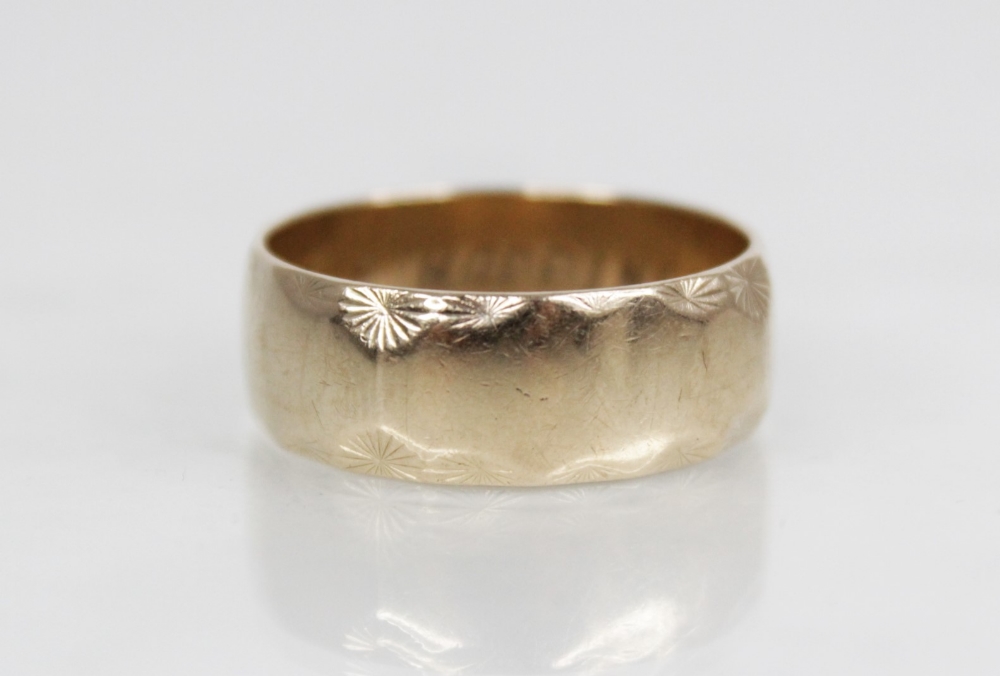 A 9ct gold wedding band, with scalloped star-cut border decoration, engraved 'YOUR HAPPINESS' to