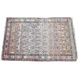 A Persian wool rug, woven in buff, red and blue dyes with an all-over stylised flower head design,