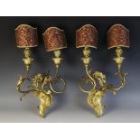 A pair of Rococo style gilt brass twin branch wall sconces, the foliate 'C' scroll back plates