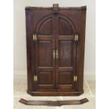 A George III oak hanging corner cupboard, the moulded cornice over a pair of arched fielded panelled