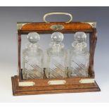A three bottle tantalus, comprising; three cut glass decanters, each approx. 23cm high, all set to