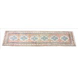 A Turkish wool runner, woven in peach, beige and blue threads with six repeating culls within a