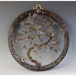 A Chinese root carved hardstone prunus wall plaque, 20th century, framed within a circular surround,