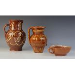 Two continental redware slip decorated water jugs, each earthenware body externally decorated with