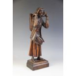 A Northern European folk art carved figure of a fisher woman, modelled standing supporting a