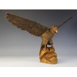 A carved wood eagle in the Black Forest manner, modelled upon a rocky outcrop with its wings spread,