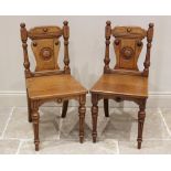 A pair of Victorian Aesthetic Movement honey oak hall chairs, each chair with button finials above a