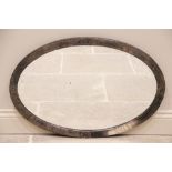 An early 20th century silver oxidised Arts and Crafts oval wall mirror, the hammered metal frame