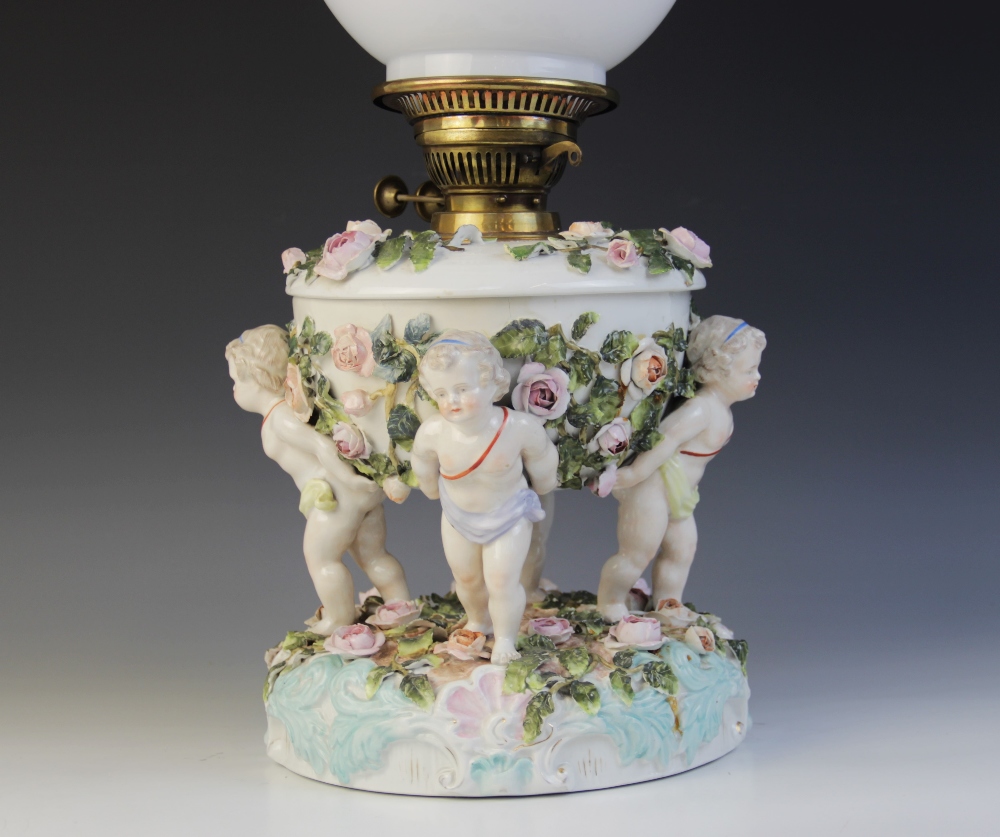 An German florally encrusted porcelain oil lamp, 19th century, modelled with four putti supporting - Image 2 of 8