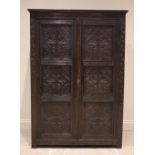 A Victorian carved oak Gothic revival hall cupboard, the pair of three panelled doors incised with