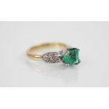 An emerald and diamond ring, the central octagonal step cut emerald measuring 7.31mm x 5.92mm,