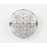 A Belle Epoque diamond set circular brooch, the white metal pierced floral design framework set with