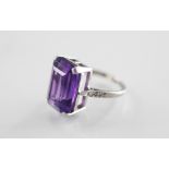 An amethyst and diamond set ring, the central step cut amethyst measuring 16mm x 11mm, claw set in