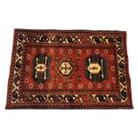 A hand woven wool carpet, with three geometric gulls in green and blue, against a deep red ground,