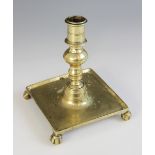 An early square form brass candlestick, possibly Dutch 17th century, the baluster knopped stem