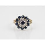 A sapphire and diamond floral cluster ring, comprising a central round mixed cut sapphire with a