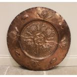 An Arts & Crafts copper embossed wall charger in the manner of John Pearson, centred with a Celtic