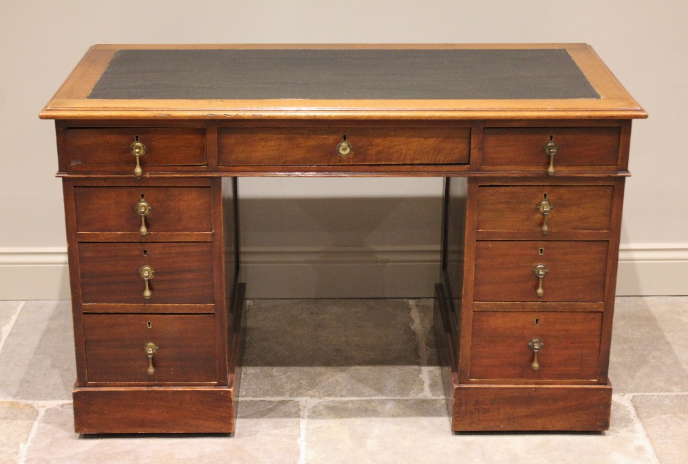 An Edwardian mahogany twin pedestal desk, the leather inset skiver above an arrangement of nine