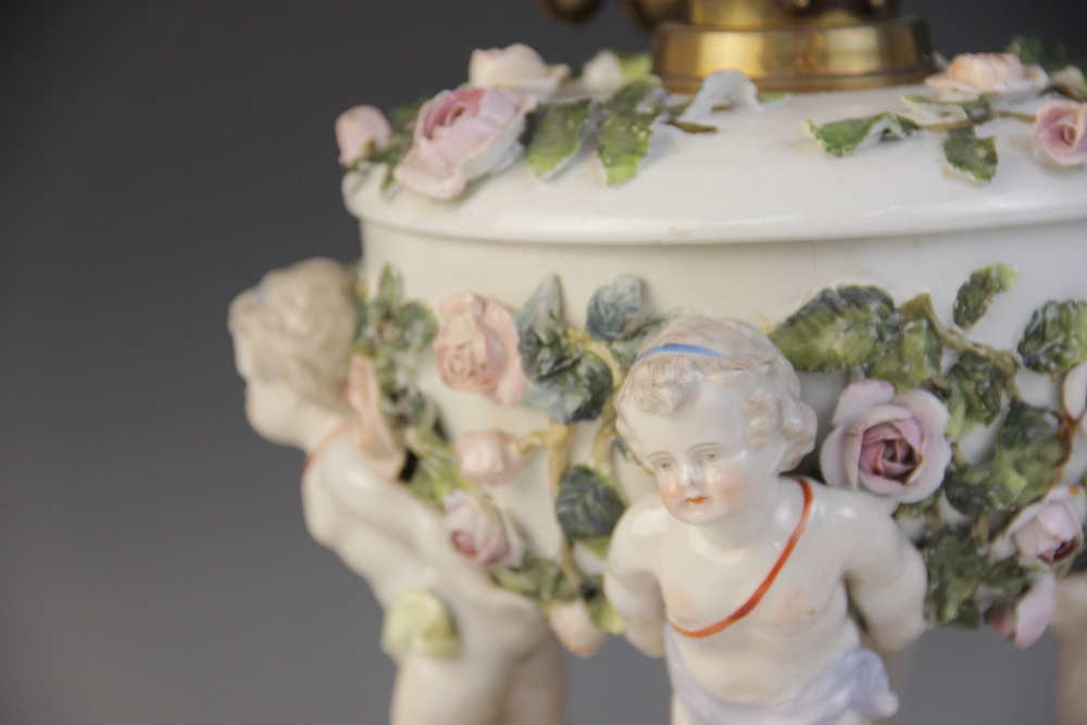 An German florally encrusted porcelain oil lamp, 19th century, modelled with four putti supporting - Image 3 of 8